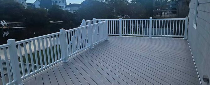 A spacious, light gray composite decking with white railings offers an elegant outdoor living area, exemplifying professional craftsmanship and high-quality materials, ideal for backyard transformation projects in Virginia Beach.| First In Decks and Fencing | Virginia Beach Deck Builders