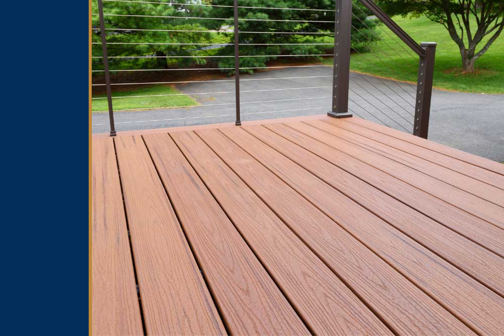 A custom deck made of high-quality composite decking with a sleek railing overlooks a lush green yard, showcasing professional craftsmanship and durable materials for an elegant outdoor living space in Virginia Beach.| First In Decks and Fencing | Virginia Beach Deck Builders