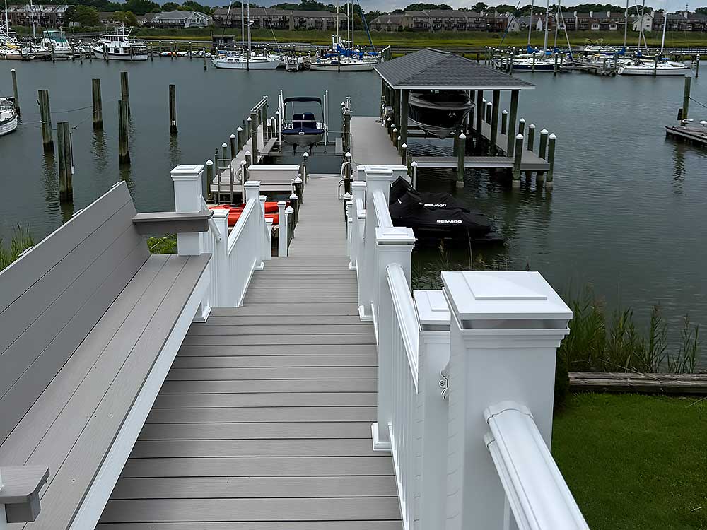 A marina with white railings leads to docks over the water, showcasing professional craftsmanship and durable materials, ideal for custom decks and outdoor living in Chesapeake.| First In Decks and Fencing | Virginia Beach Deck Builders